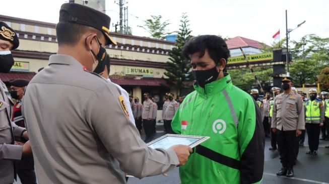 Driver Gojek Makassar Rafles Kristianto Boway mendapat penghargaan dari Kapolrestabes Makassar, Rabu 9 Maret 2022 [SuaraSulsel.id/Dokumentasi Gojek Makassar]